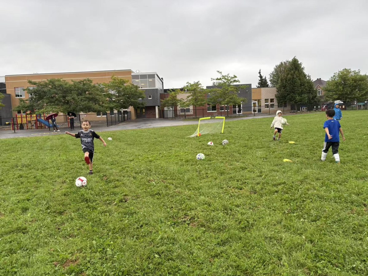 Young player kicking the ball during rainy soccer practice